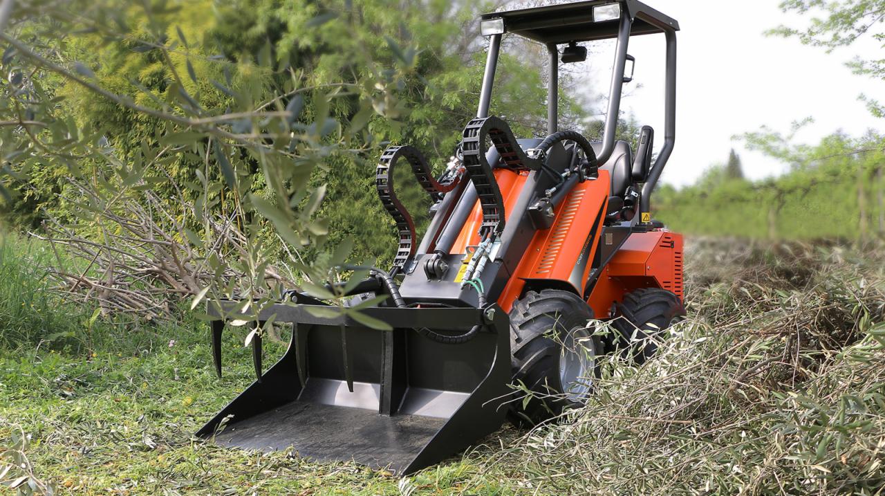 Pomarańczowa maszyna z czarnym osprzętem zbiera gałęzie na trawiastym terenie, widok z perspektywy operatora.