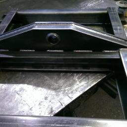 Salda-col - Metalowa konstrukcja spawana z profili stalowych, widoczne spoiny, szlifierka kątowa w tle.