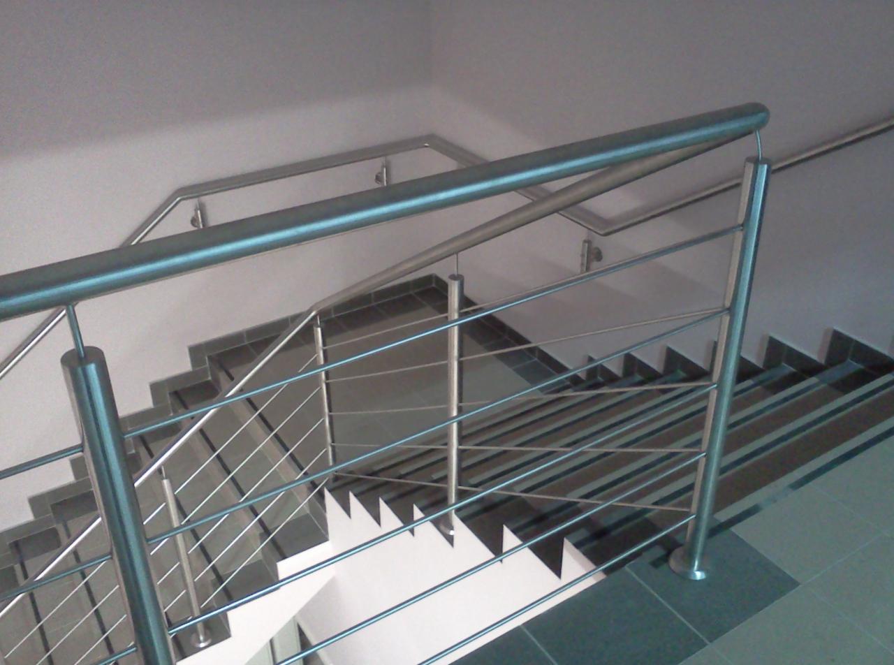 Wewnętrzne schody z nowoczesną balustradą ze stali nierdzewnej, widok z góry, ciemne płytki na stopniach i podłodze.