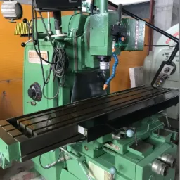 Zielona frezarka uniwersalna Elliott z cyfrowym odczytem położenia, widoczne metalowe elementy i przewody chłodzenia, w tle fragment hali produkcyjnej.