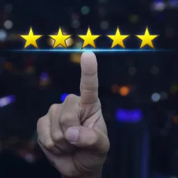 Wskazujący palec dotyka pięciu złotych gwiazdek na rozmytym tle miejskich świateł, symbolizujących najwyższą ocenę lub doskonałą jakość usług.