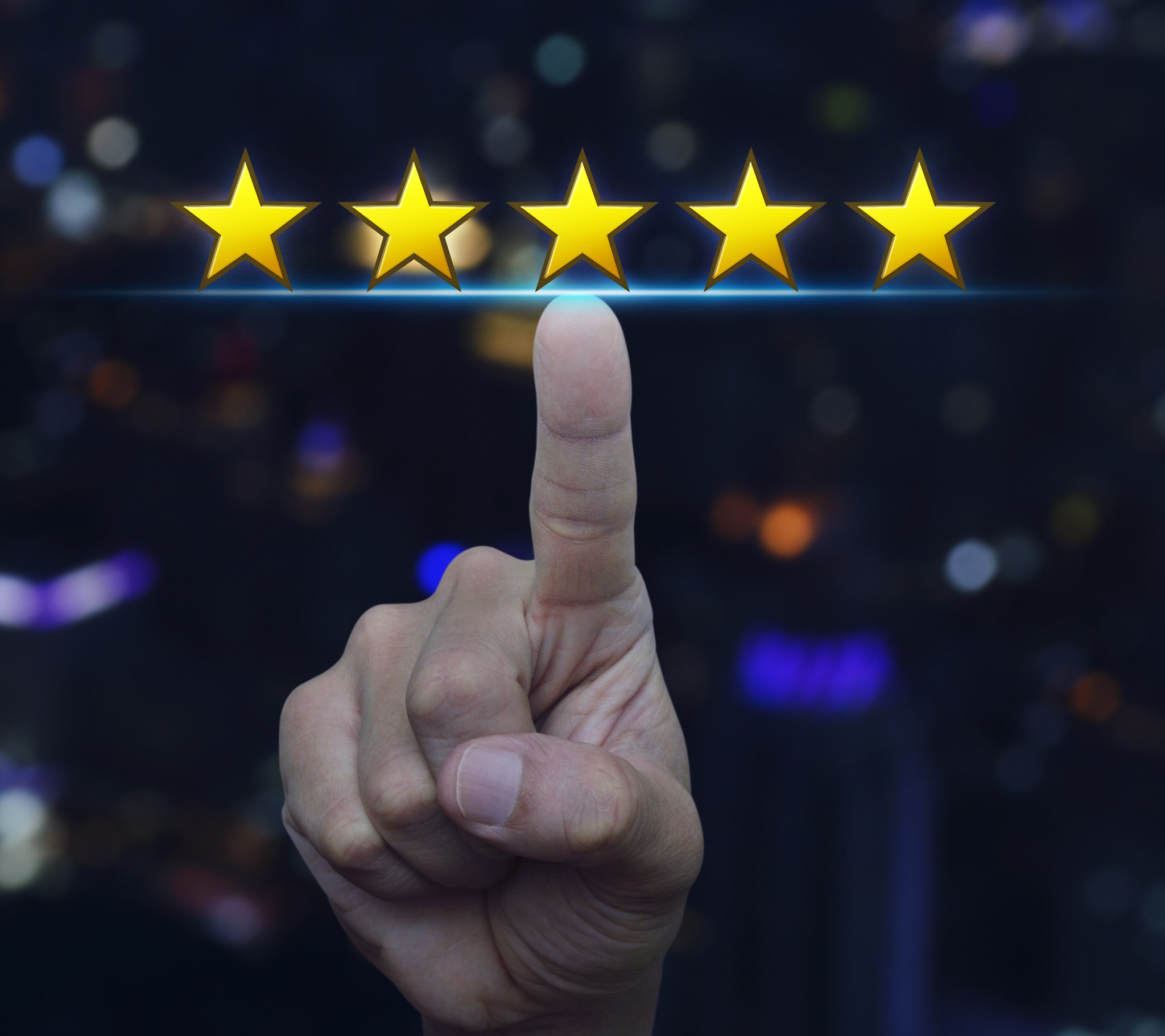 Wskazujący palec dotyka pięciu złotych gwiazdek na rozmytym tle miejskich świateł, symbolizujących najwyższą ocenę lub doskonałą jakość usług.