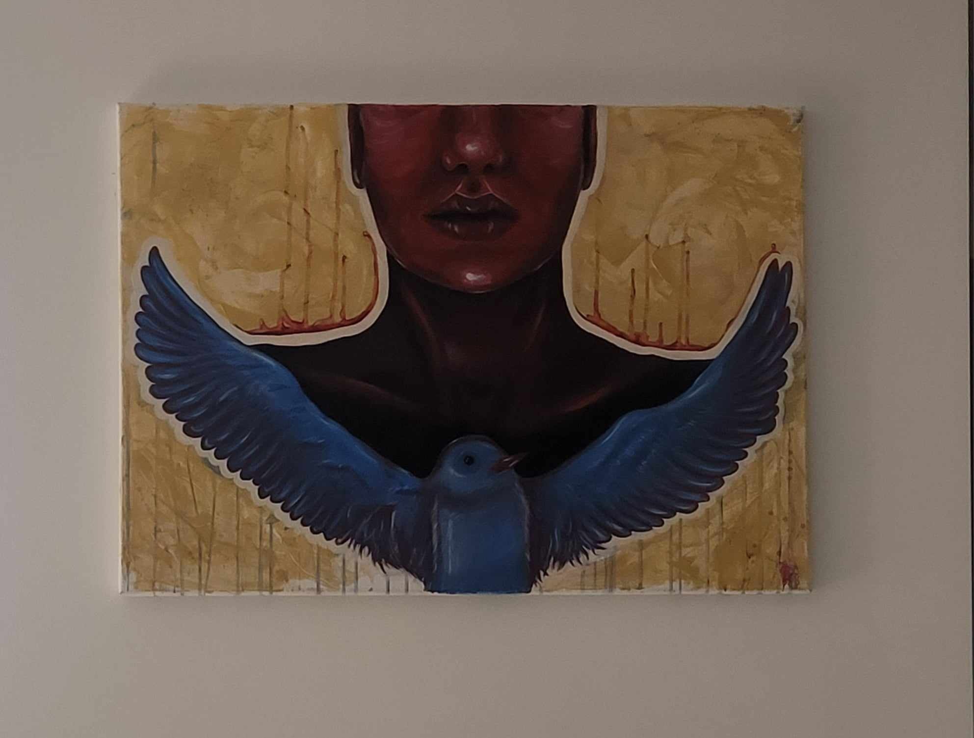 Abstrakcyjny obraz olejny przedstawiający ciemnoczerwoną twarz bez oczu nad niebieskim ptakiem z rozpostartymi skrzydłami na złotym tle z pionowymi smugami, wiszący na białej ścianie.