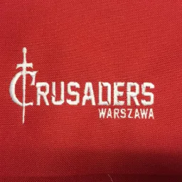 Czerwona tkanina z białym, precyzyjnym haftem napisu 'Crusaders Warszawa' z stylizowanym krzyżem.