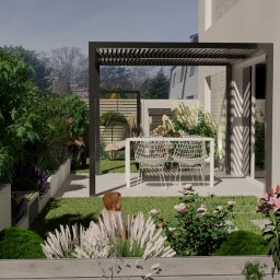 OGRODOWY KREATOR Iwona Falęcka - Nowoczesny ogród z pergolą, stołem i krzesłami. Bujna roślinność, w tym kwiaty i drzewa, tworzy przytulną atmosferę. Widoczny fragment domu z białymi ścianami.