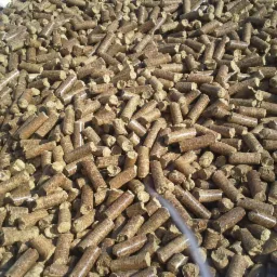 Góra pelletu drzewnego w jasnym oświetleniu. Widoczne detale struktury pelletu i jego brązowy odcień. Całość kadru wypełniona, bez elementów otoczenia.