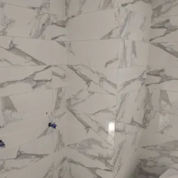 Ściana łazienki wyłożona białymi płytkami imitującymi marmur, widoczne otwory na baterie z zabezpieczeniami.