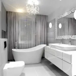Elegancka, jasna łazienka z wolnostojącą wanną, umywalką nablatową na szafce z szufladami, ozdobnym lustrem w białej ramie i żyrandolem.