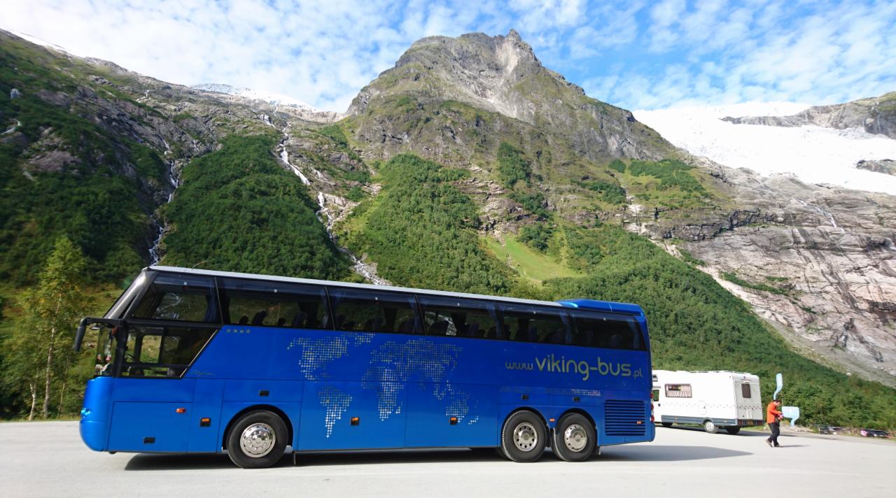Niebieski autokar z mapą świata na boku i logo 'www.viking-bus.pl' na tle górskiego krajobrazu z lodowcem.
