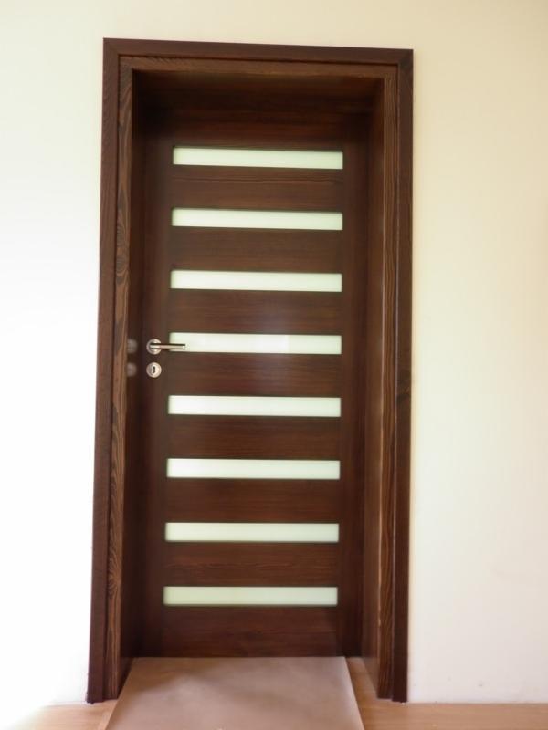 Ciemnobrązowe drzwi wewnętrzne z poziomymi, mlecznymi przeszkleniami i srebrną klamką, zamontowane w jasnej ścianie, widoczne w całości.