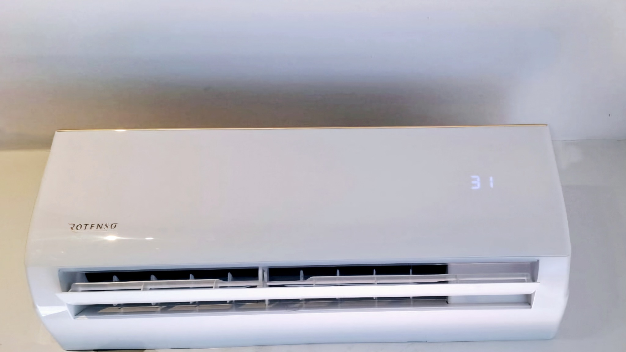 Biały klimatyzator marki Rotenso zamontowany na ścianie, wyświetlający temperaturę 31 stopni Celsjusza.