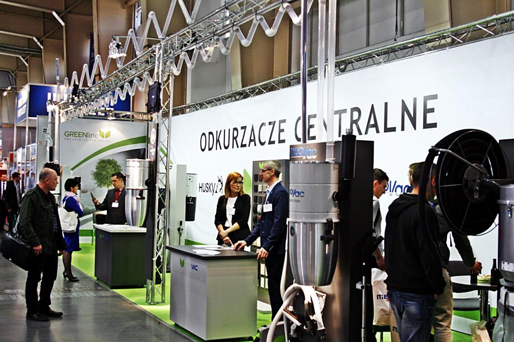Stoisko targowe z odkurzaczami centralnymi marek GreenLine, Husky i DuoVac. Widoczni ludzie, ekspozytory i elementy konstrukcyjne stoiska na tle hali.