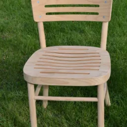 Jasne, drewniane krzesło ogrodowe z ażurowym siedziskiem i oparciem, ustawione na trawie.