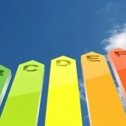 Kolorowe słupki z literami A-G na tle błękitnego nieba, symbolizujące klasy efektywności energetycznej, od zielonej (A) do czerwonej (G).