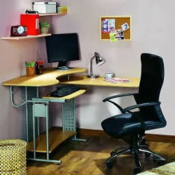 Kącik biurowy z jasnym biurkiem narożnym, ergonomicznym krzesłem i półkami z dekoracjami, oświetlony lampką biurkową.