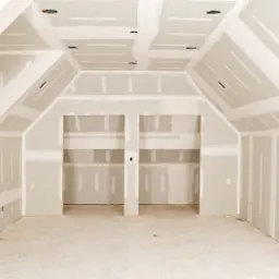 Pokój na poddaszu w trakcie szpachlowania płyt gipsowo-kartonowych, widoczne otwory na oświetlenie i wnęki w ścianie.