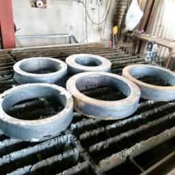 Anstal - Metalowe pierścienie po cięciu plazmą, ułożone na stole roboczym z charakterystycznym wzorem. Widoczne ślady obróbki i minimalne nierówności krawędzi.