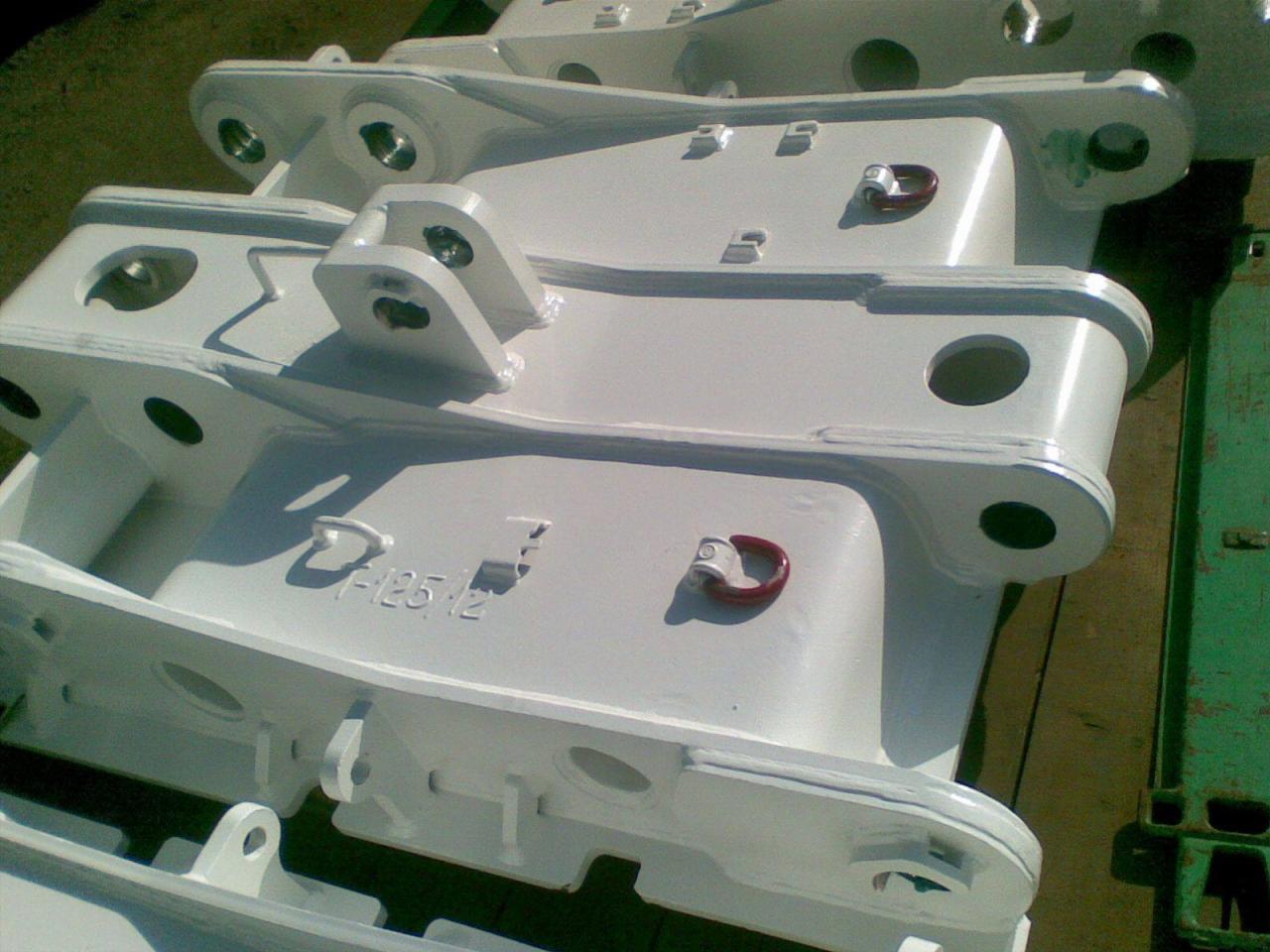 Białe, metalowe elementy konstrukcyjne z uchwytami i otworami, ułożone warstwami, widoczne oznaczenia 'D-125-12'.