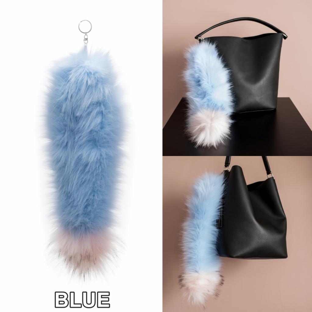 Błękitny, puszysty brelok z futra z różowo-białym końcem, zawieszony obok czarnej torebki na dwóch ujęciach.