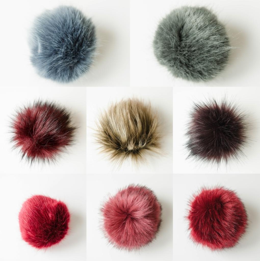 Kompozycja dziewięciu puszystych pomponów z imitacji futra w różnych kolorach: szaroniebieskim, szarozielonym, bordowym, beżowym, ciemnobordowym, intensywnie czerwonym i dwóch odcieniach malinowej...