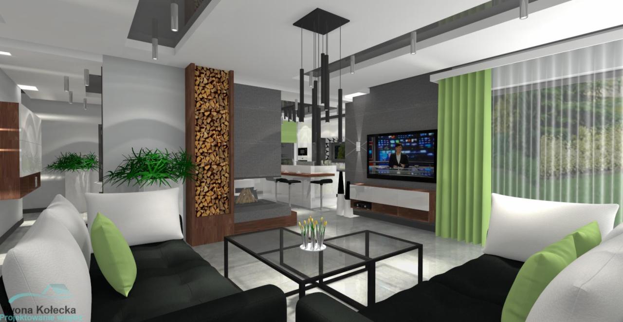 Wizualizacja salonu z kominkiem obłożonym drewnem, czarnymi sofami z zielonymi poduszkami, szklanym stolikiem kawowym i otwartą kuchnią w tle.