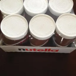 Sześć słoiczków kremu Nutella w kartonowym opakowaniu, widoczne białe nakrętki z napisem Nutella i logo kontroli jakości.