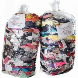 Dwa przezroczyste worki foliowe wypełnione odzieżą z widocznymi etykietami i kartkami informacyjnymi, ustawione obok siebie na białym tle.