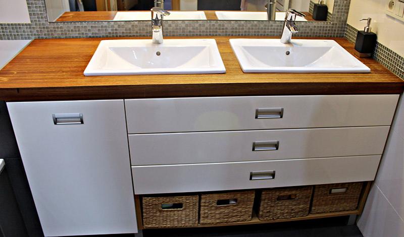 Łazienka z dwiema umywalkami nablatowymi na drewnianym blacie, białe szafki z szufladami i koszami z wikliny, mozaika na ścianie.