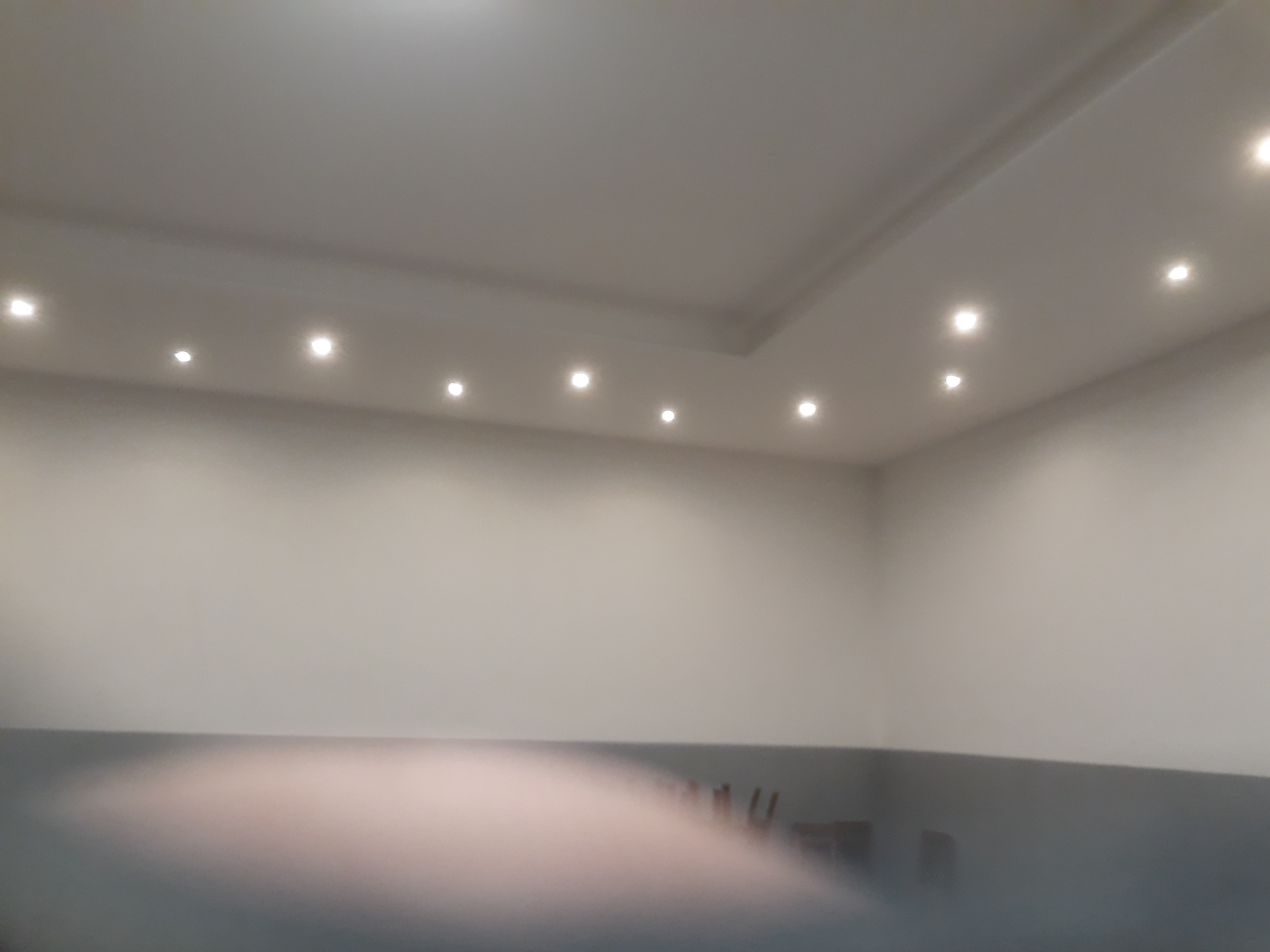 Pomieszczenie po gładziowaniu ścian i sufitu z widocznym oświetleniem punktowym w suficie podwieszanym.