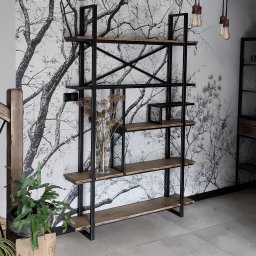 Firma Indust - Regał w stylu industrialnym z czarną metalową konstrukcją i drewnianymi półkami, na tle ściany z motywem drzew, z dekoracjami w postaci suszonych kwiatów w wazonie i roślin doniczkowych.