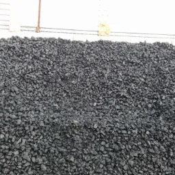 Góra czarnego, błyszczącego węgla kamiennego na składzie, widoczna tekstura i nieregularny kształt bryłek.