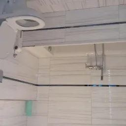 Nowoczesna łazienka z białymi, poziomymi płytkami imitującymi drewno, podwieszana toaleta, chromowana bateria prysznicowa i półka z umywalką.