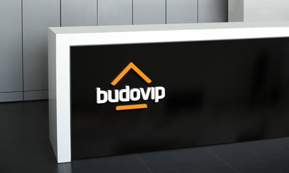 Recepcja z podświetlanym logo 'budovip' w kolorach białym i pomarańczowym na czarnym tle, nowoczesny design.