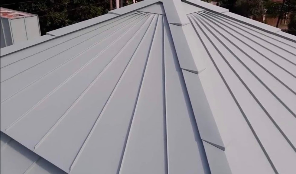 Nowoczesne, metalowe pokrycie dachowe w jasnoszarym odcieniu, z wyraźnie zaznaczonymi panelami i liniami łączeń, widziane z góry pod kątem.