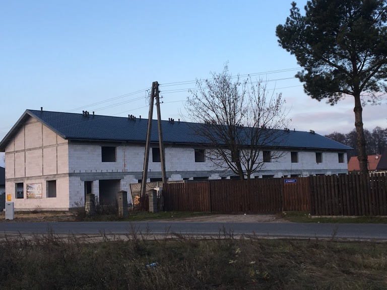 Szeregowiec w trakcie budowy w Głogowie koło Torunia z położonym ciemnym pokryciem dachowym, widoczne bloczki betonowe, okna jeszcze niezamontowane.