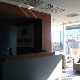 Wnętrze biura Getin Noble Bank po przebudowie: recepcja z logo, widok na miasto przez duże okna, nowoczesne fotele w strefie oczekiwania.