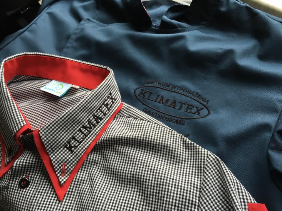 Koszula w drobną kratę z czerwonym kołnierzykiem i wyhaftowanym napisem 'KLIMATEX' oraz granatowa bluza z wyhaftowanym logo 'KLIMATEX CENTRUM WYPOSAŻENIA GASTRONOMII'.