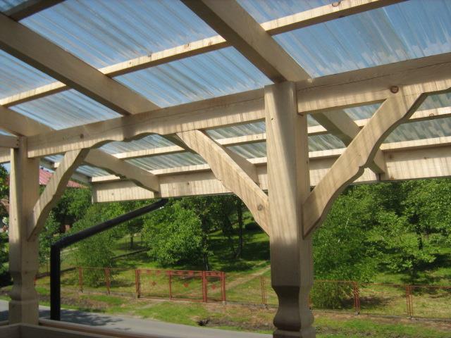 Drewniana konstrukcja z przezroczystym zadaszeniem, widok z dołu, na tle zieleni