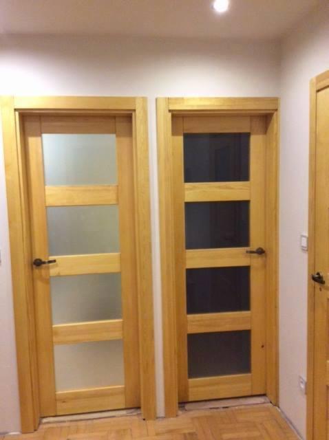 Dwa drewniane drzwi wewnętrzne z trzema przeszkleniami, jeden z matowym szkłem, drugi z ciemnym, widok na fragment trzecich drzwi.