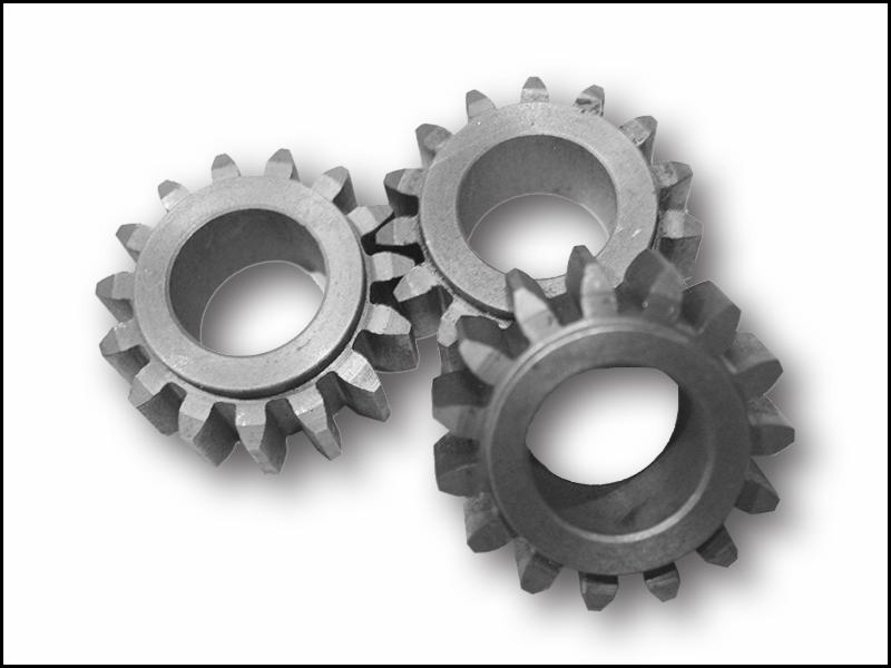 Trzy metalowe koła zębate w zbliżeniu, ułożone blisko siebie na białym tle, rzucające delikatny cień.