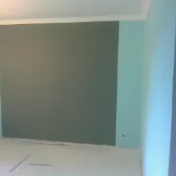 Pokój po malowaniu: szara ściana akcentowa otoczona turkusowymi ścianami, biały sufit z listwą dekoracyjną, podłoga zabezpieczona folią malarską.