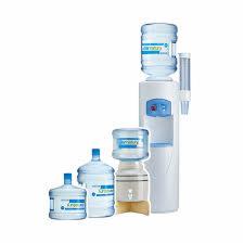 Trzy butle z wodą mineralną o różnych pojemnościach ustawione obok dystrybutora wody z zamontowaną butlą. Dystrybutor w kolorze białym z niebieskimi elementami.