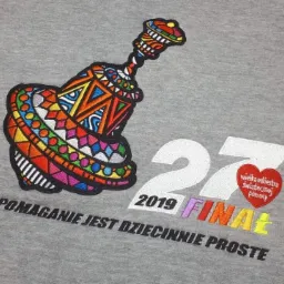 Szara koszulka z kolorowym, haftowanym wzorem przedstawiającym logo Wielkiej Orkiestry Świątecznej Pomocy, rok 2019, napis 'Pomaganie jest dziecinnie proste'.