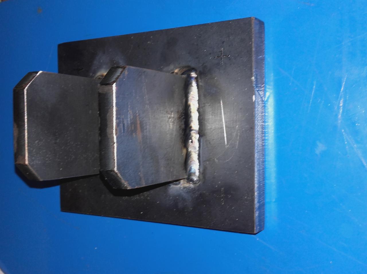 Spoina na metalowym elemencie wykonana w Borowie, widoczna na niebieskim tle.