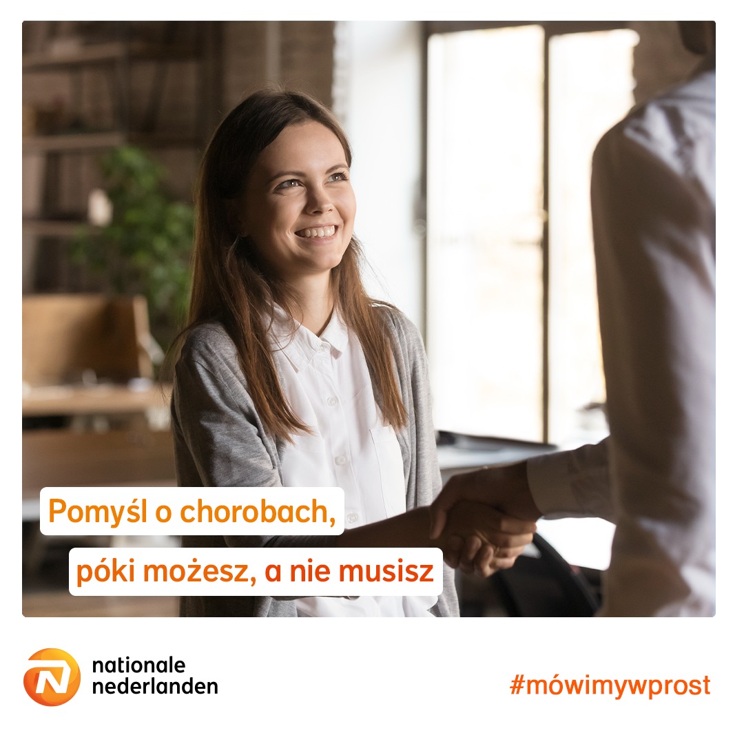 Uśmiechnięta kobieta w jasnej bluzce i szarym kardiganie wita się z mężczyzną, w tle biuro z roślinami.