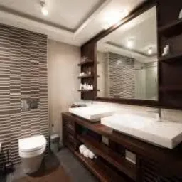 Nowoczesna łazienka z dwoma umywalkami na ciemnym drewnianym blacie, podświetlane lustro, ściana wyłożona poziomymi płytkami imitującymi drewno, bidet po lewej stronie.