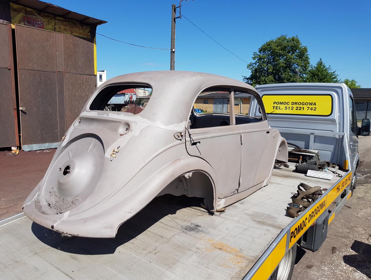 Karoseria starego samochodu przed renowacją, załadowana na lawetę w Lipnie. Widoczne ślady rdzy i przygotowania do obróbki.