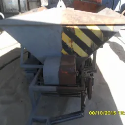 Urządzenie do obróbki powierzchni z charakterystycznymi żółto-czarnymi pasami ostrzegawczymi, widoczne ślady rdzy i niedokładnego malowania, stojące na piaszczystym podłożu.