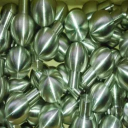 Partia obrobionych, metalowych kul z trzpieniami, widoczne ślady obróbki skrawaniem.