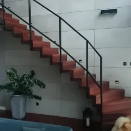 Nowoczesne schody drewniane z czarną balustradą w minimalistycznym wnętrzu, z psem rasy Chow Chow spoglądającym przez okno z żaluzjami.